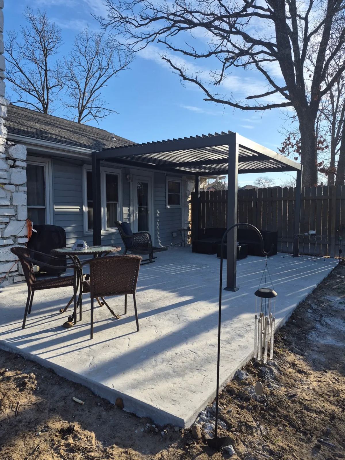 New extended concrete patio with modern louvered pergola